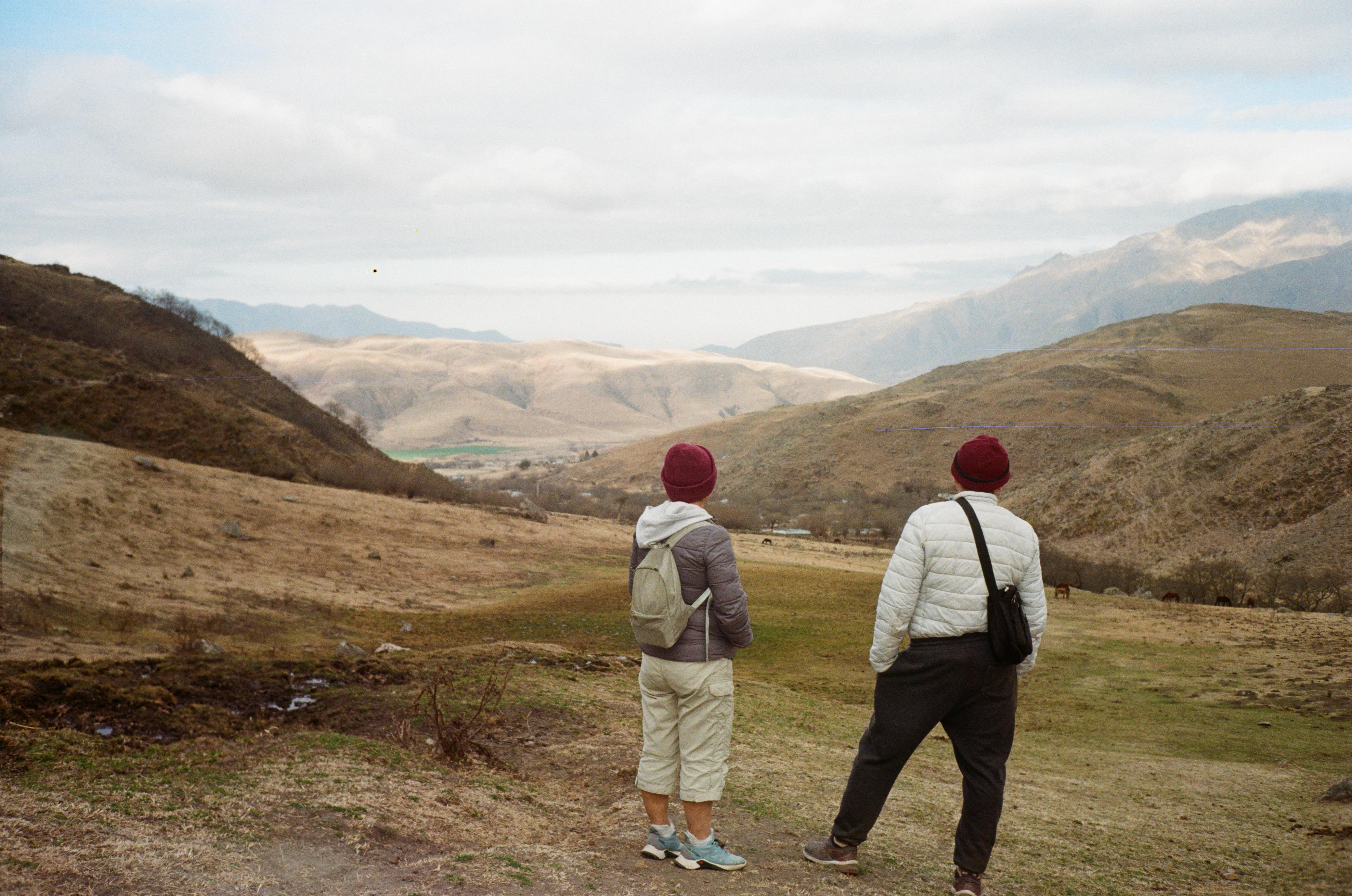 Mujer sentada sobre un tronco frente a una cascada doble en un bosque frondoso de Argentina.