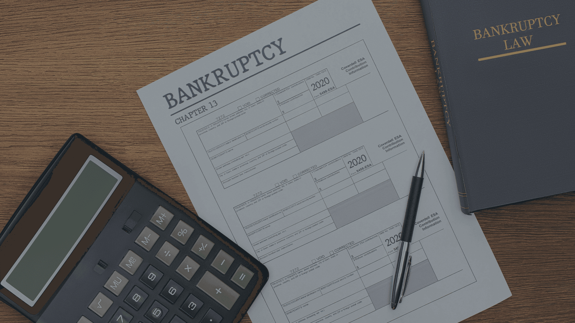 Bankruptcy filing forms, calculator, and bankruptcy law book on a desk, representing Chapter 7 and Chapter 13 bankruptcy relief services at Lamb & Lamb, P.C. in Salem, MA