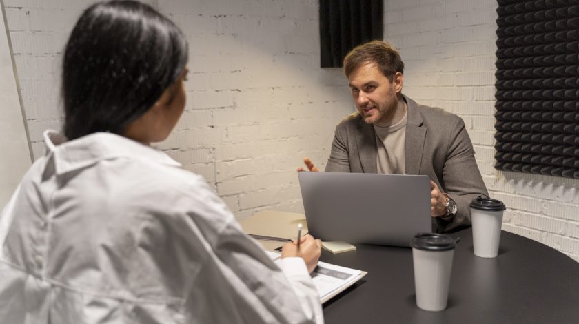 A man and a woman playing Jenga, carefully pulling out a block from a tall stack.