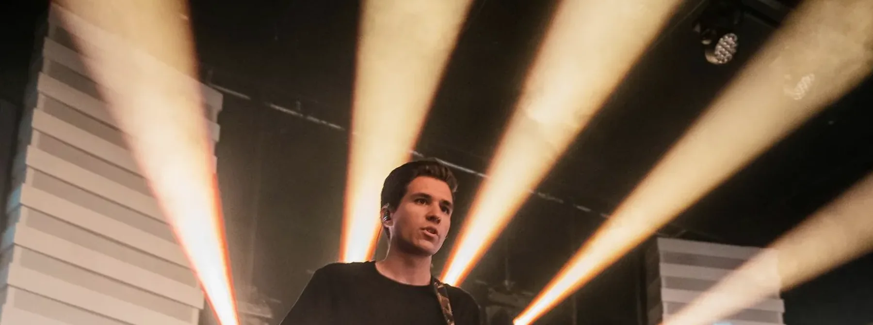 A guitarist on stage in front of beams of light