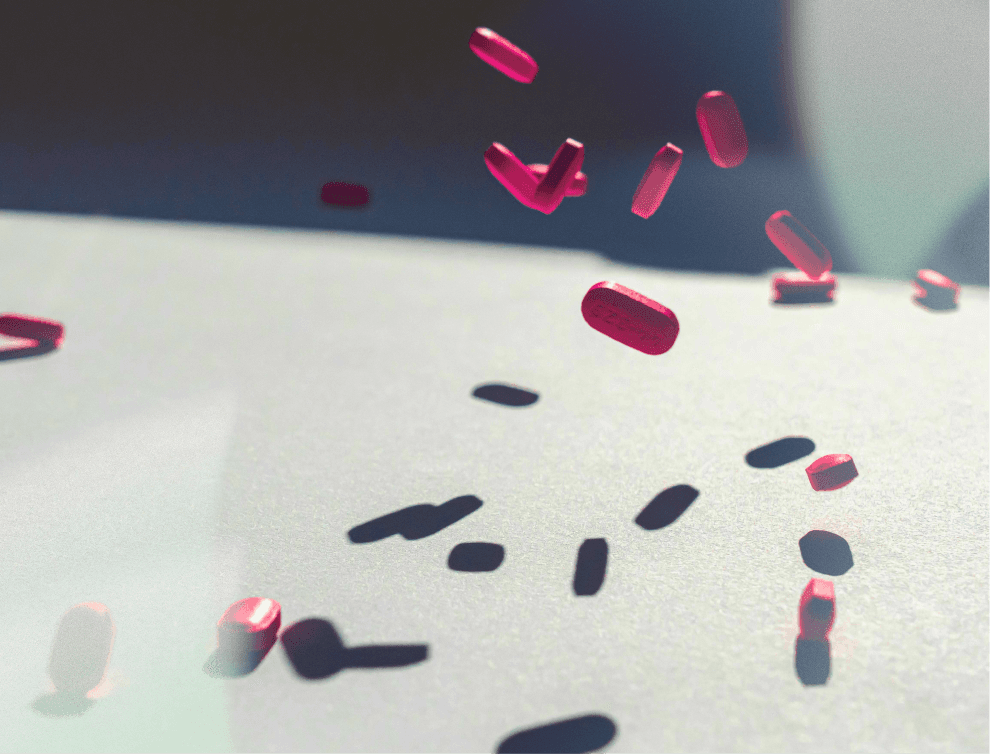 A winding road cuts through rocky terrain, surrounded by patches of green grass and illuminated by sunlight.