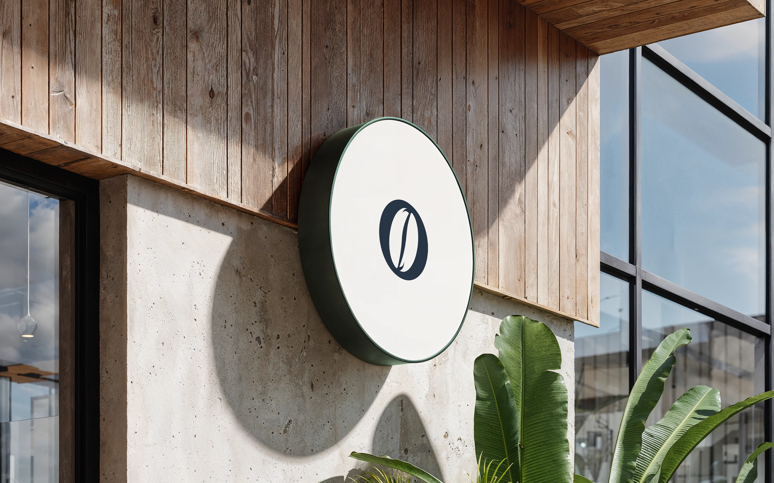 Minimalist circular outdoor wall sign featuring the 'O' logo mark mounted on a wooden cafe facade.
