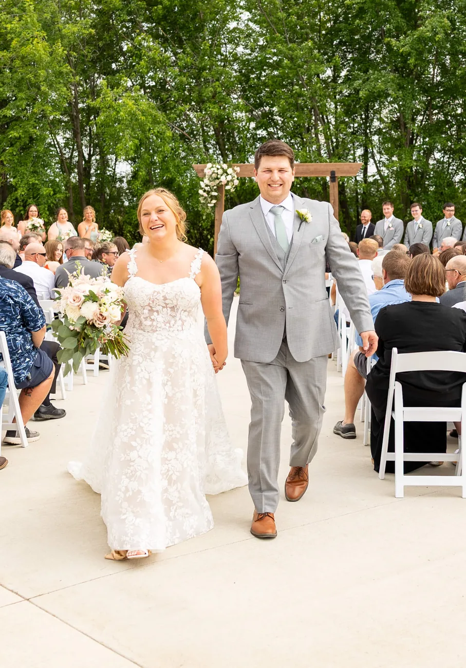 Bride and groom smiling as they walk back up the aisle after their ceremony, by Sioux Falls, SD wedding photographer Kelsey Lynn
