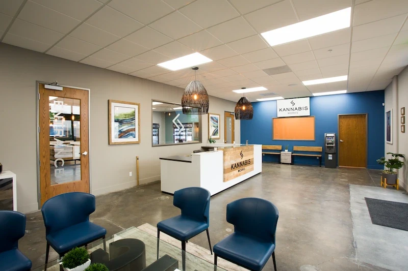 Interior view of Kannabis Works with reception desk, blue chairs, and vibrant orange accent wall.
