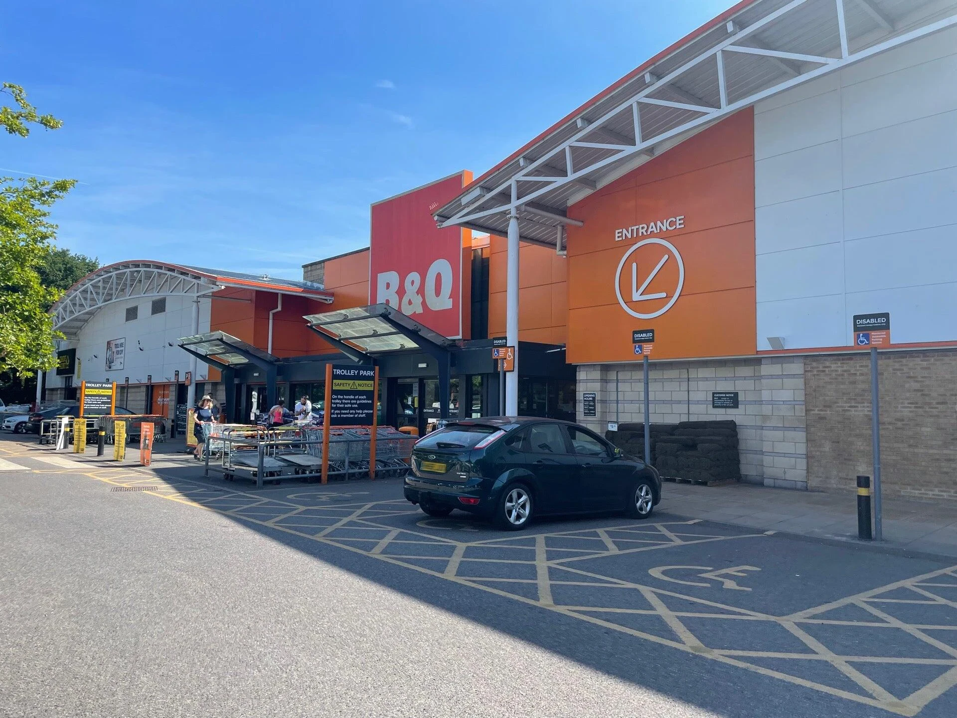 A group of construction workers wearing high-visibility jackets and hard hats celebrate at a construction site with safety signs and equipment visible in the background.