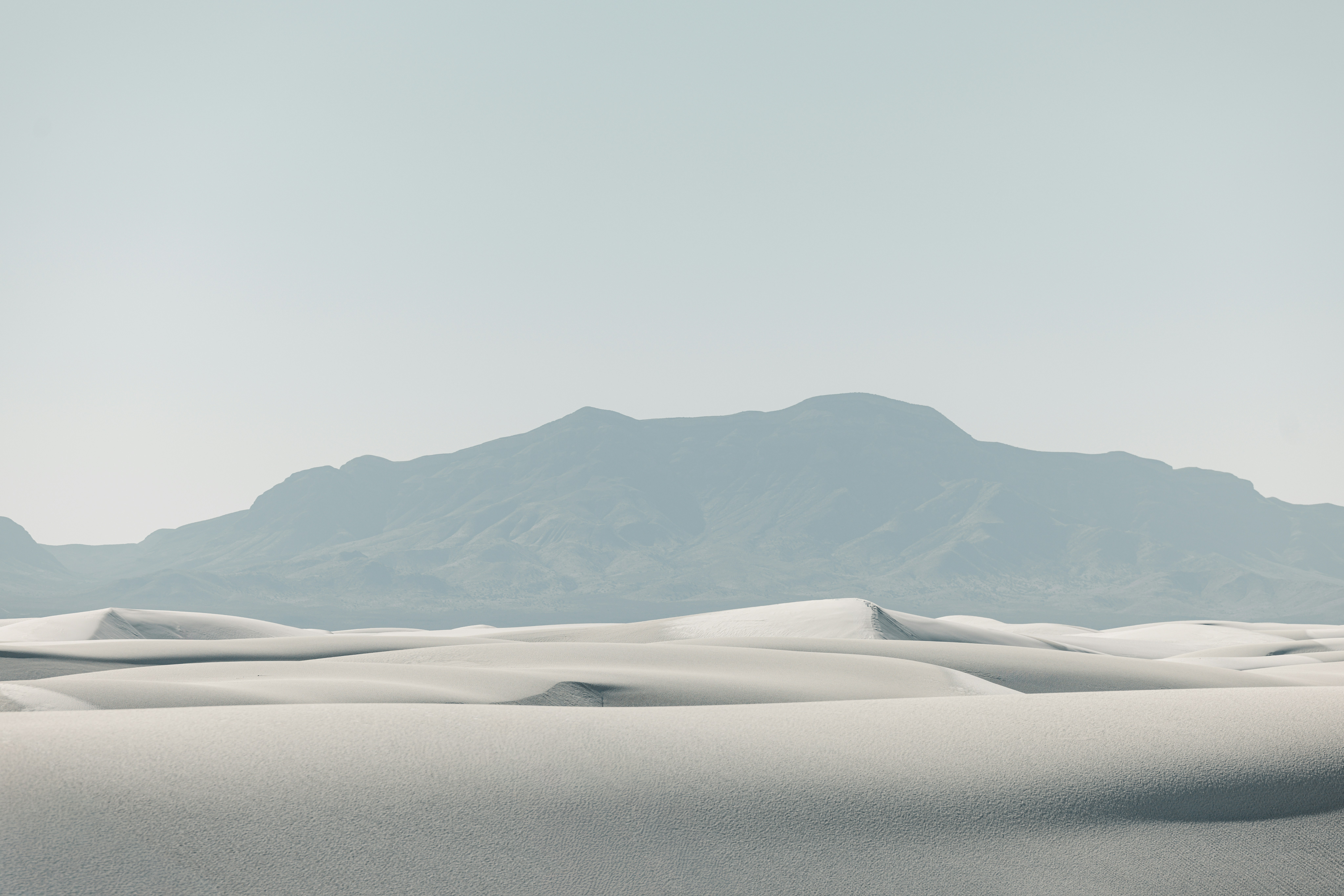 White sand dunes with a distant mountain range.