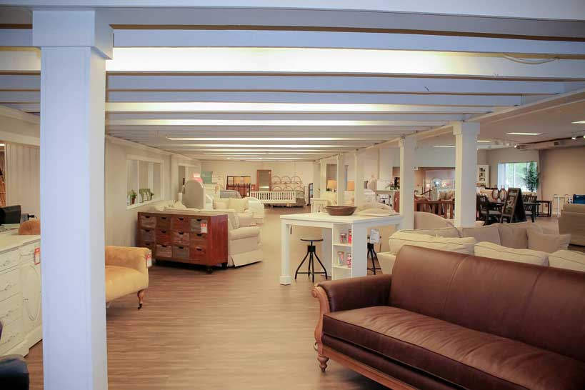 Bright, modern showroom space featuring brown furniture and an open layout with various decorative elements.