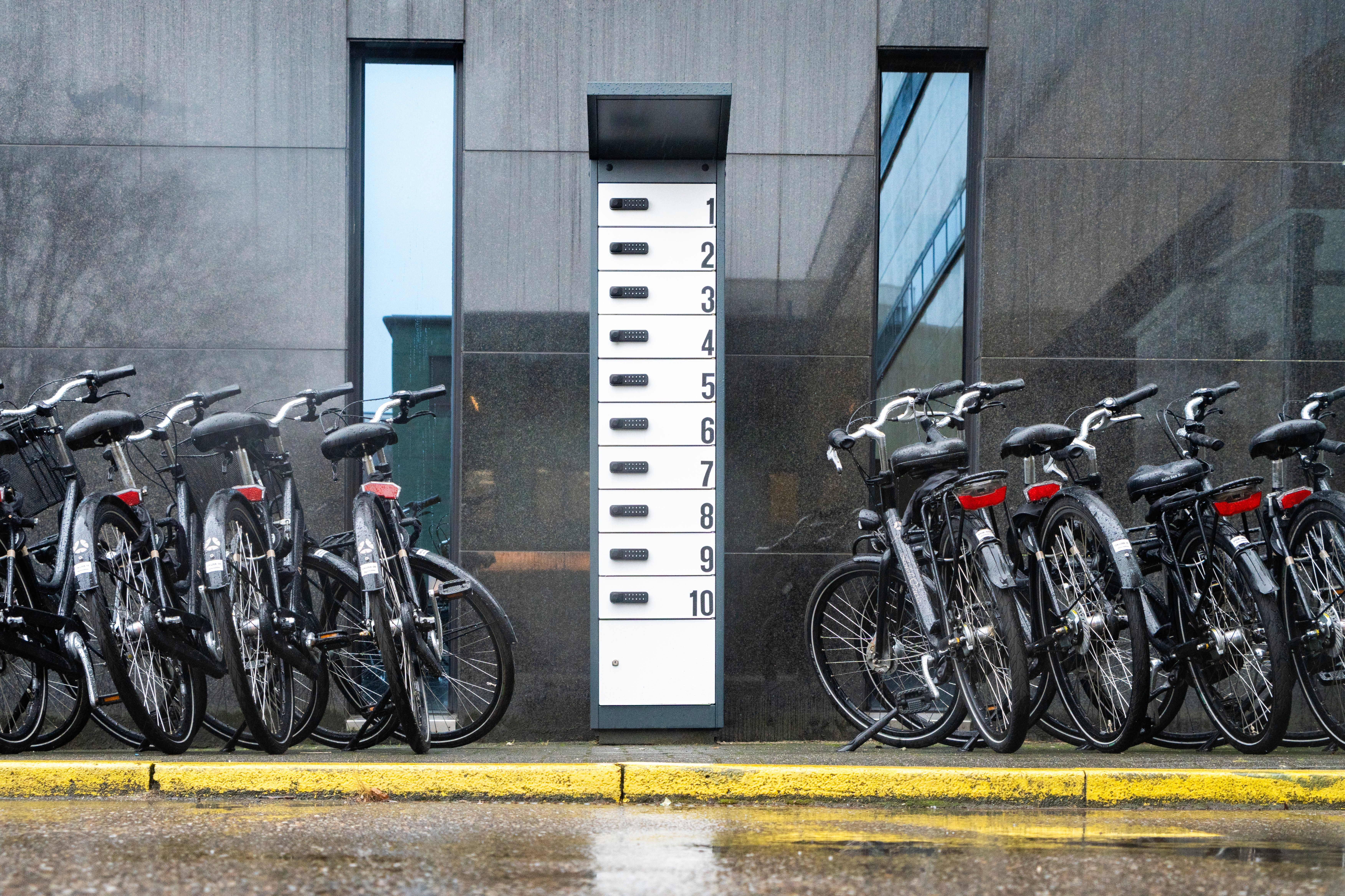 A professional PowerShelter e-bike battery charging locker with 10 secure compartments, situated between parked bikes at a luxury hotel property.