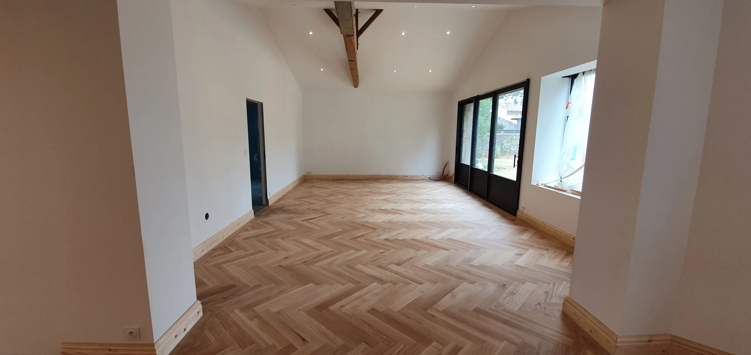 Pièce rénovée avec parquet chêne en point de Hongrie et poutre apparente, réalisation Aliénor Parquet en Gironde