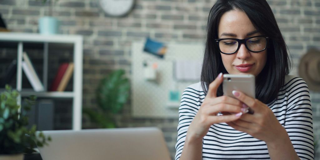 a woman wearing glasses looking at her cell phone