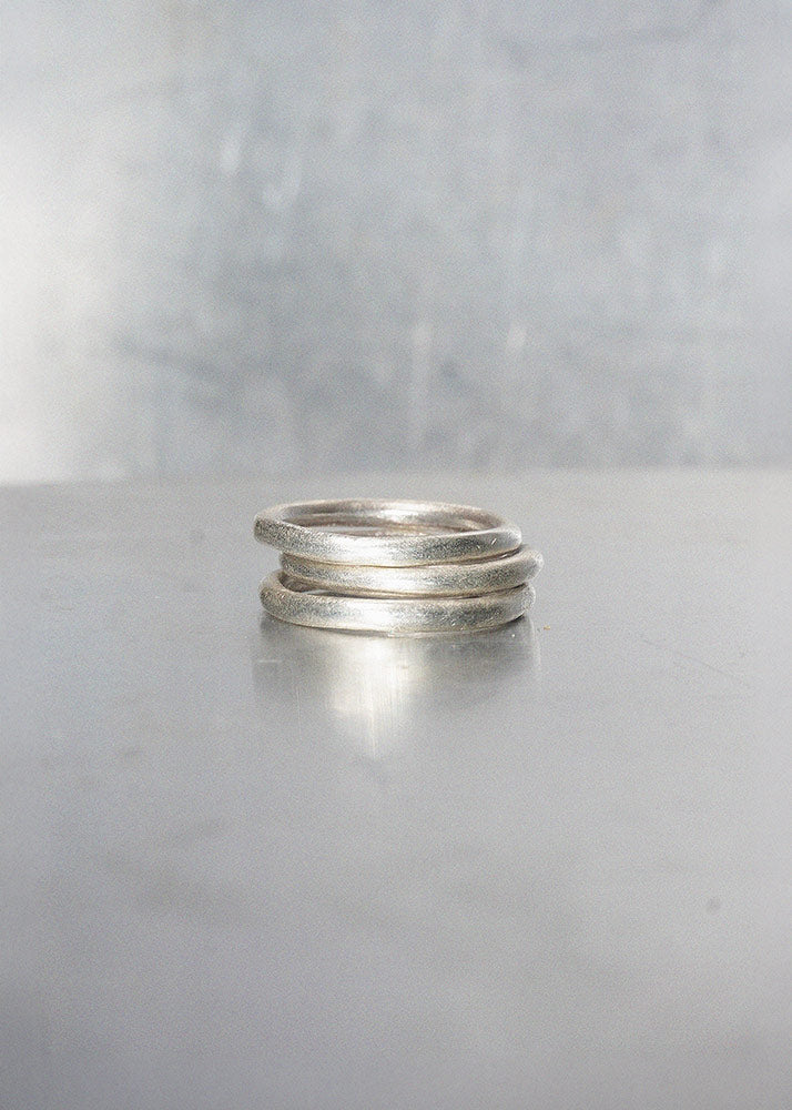 Three silver rings stacked on a gray surface with a neutral background