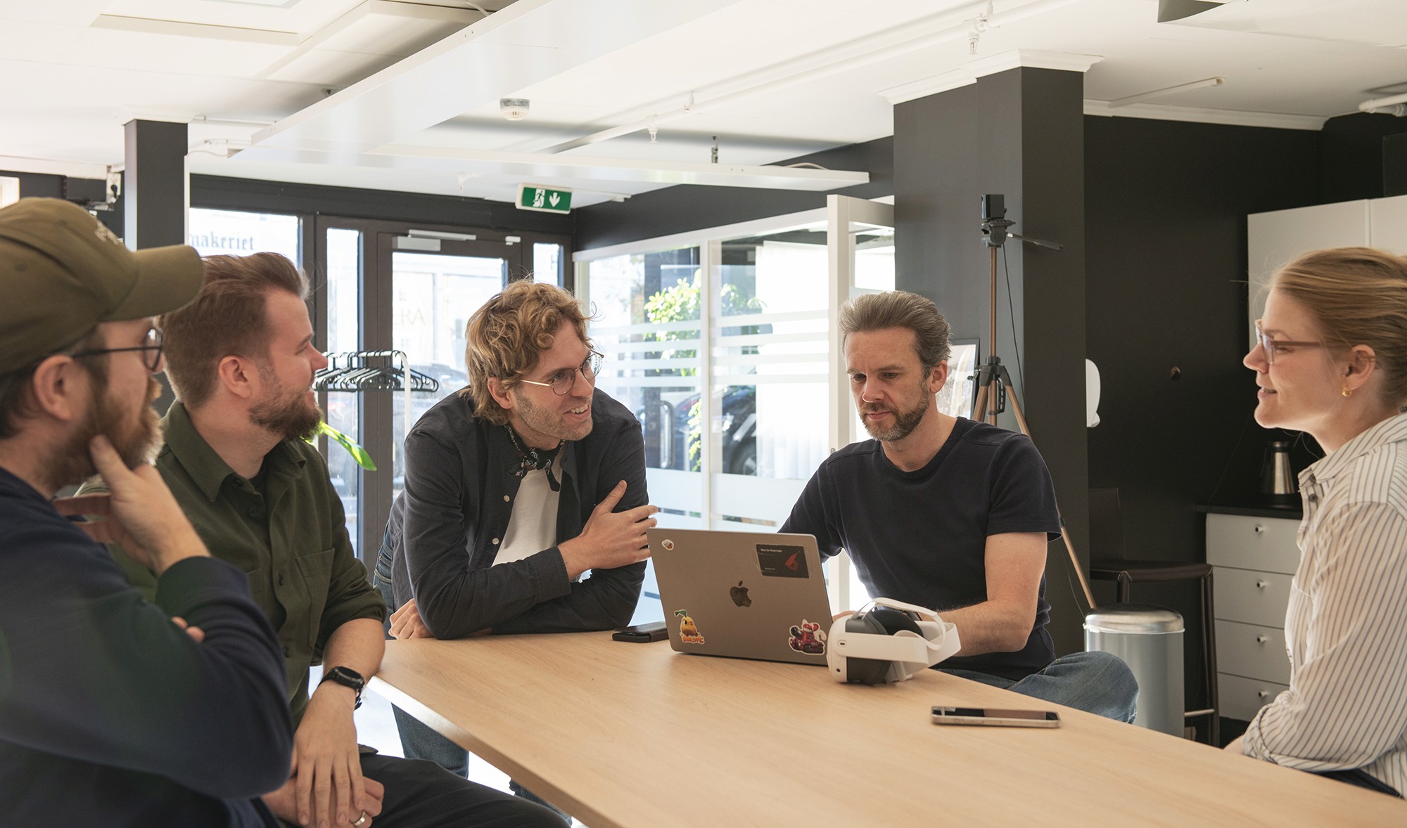 A diverse team collaborates around a table, analyzing documents and charts in a professional setting with a light green background.