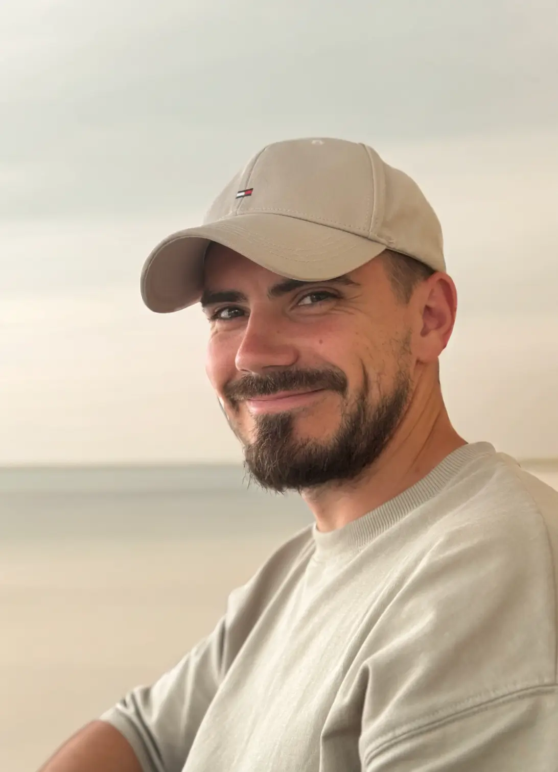 A smiling hadnsome young man, wearing a cap