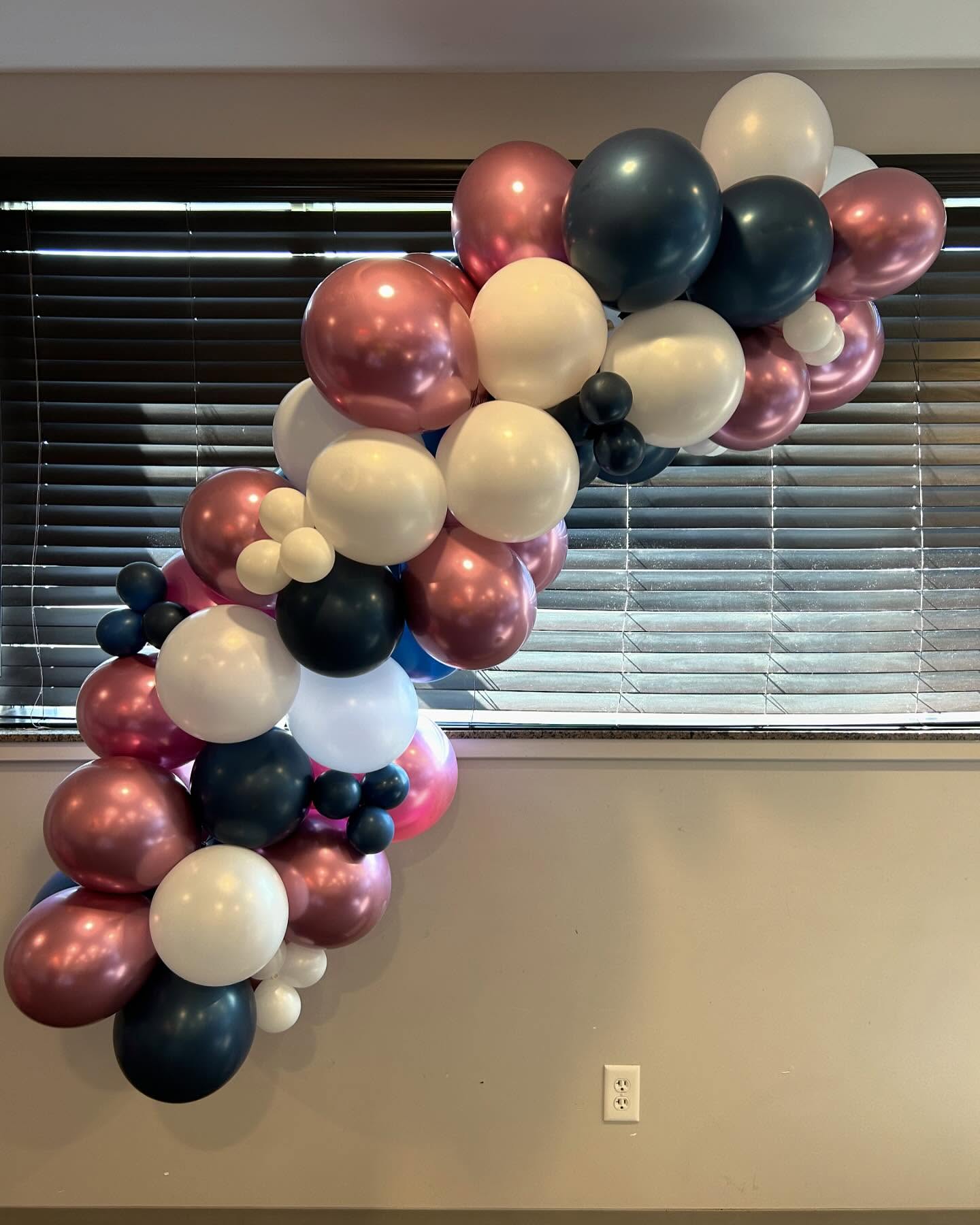 Balloon garland with black, gold, and rose gold balloons arranged along a window for an indoor event by Be Bold Balloons
