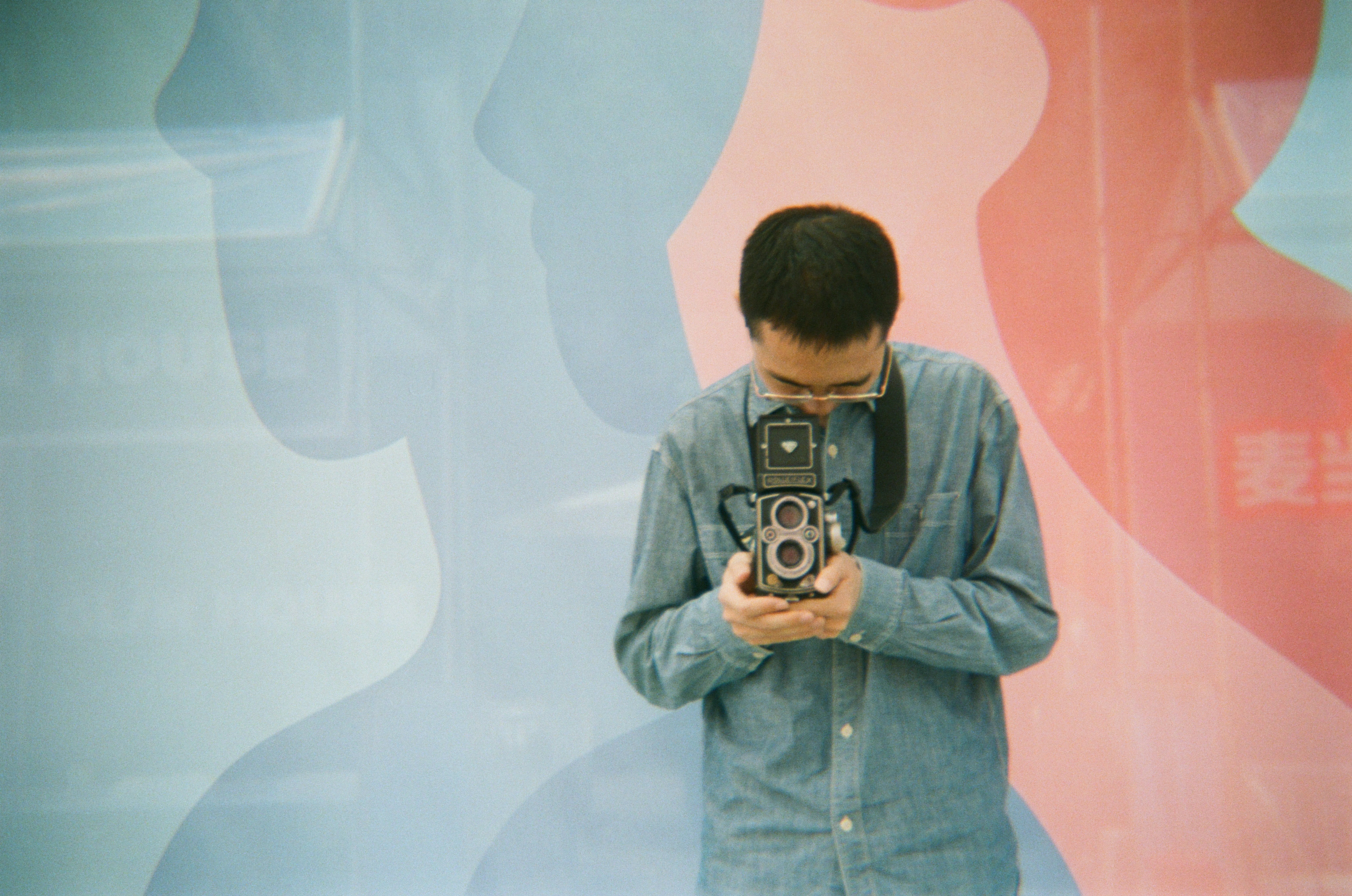 Man holding vintage camera in front of colorful abstract background