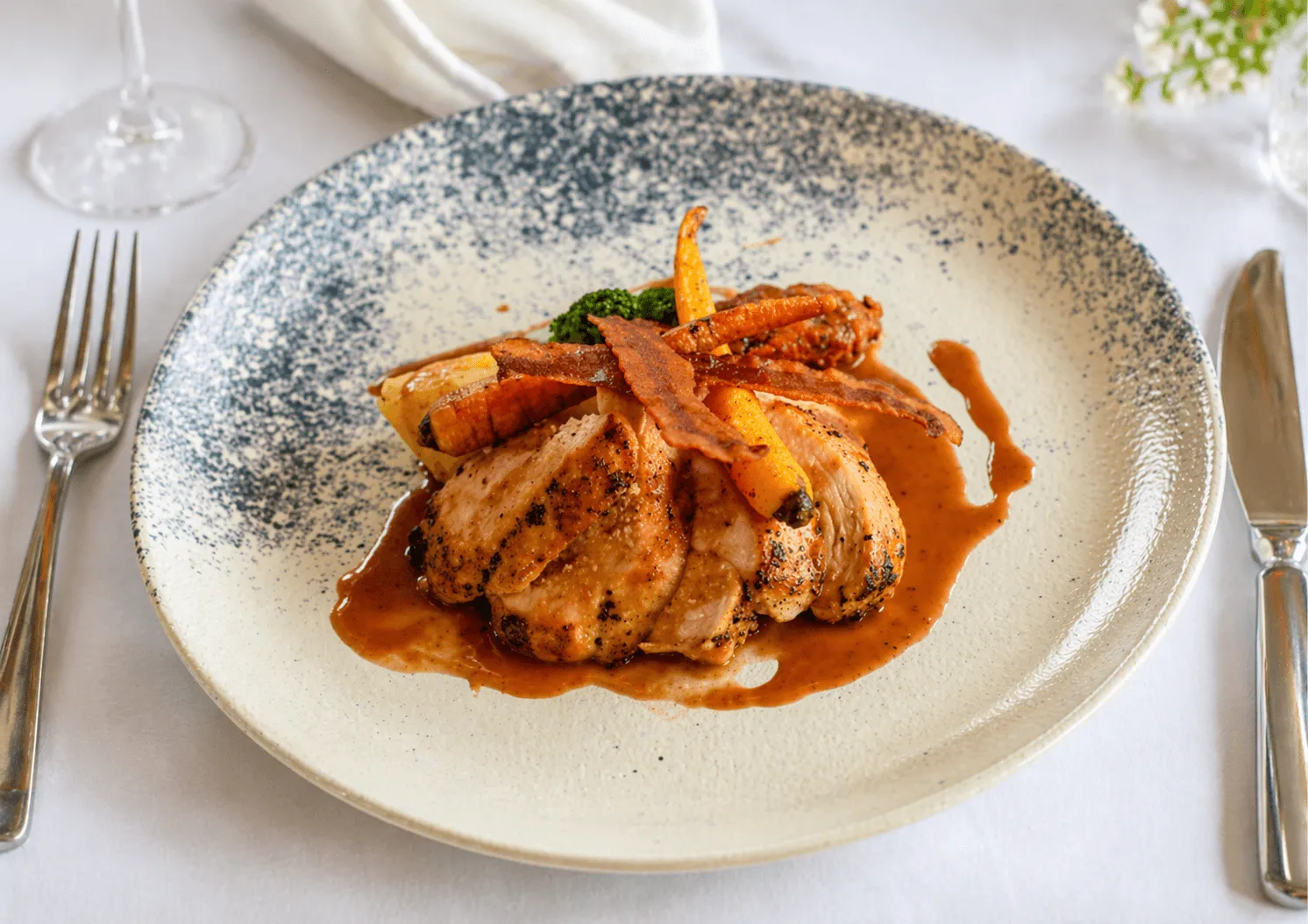 Plated dish features sliced meat with sauce,  carrots,  bacon,  potato