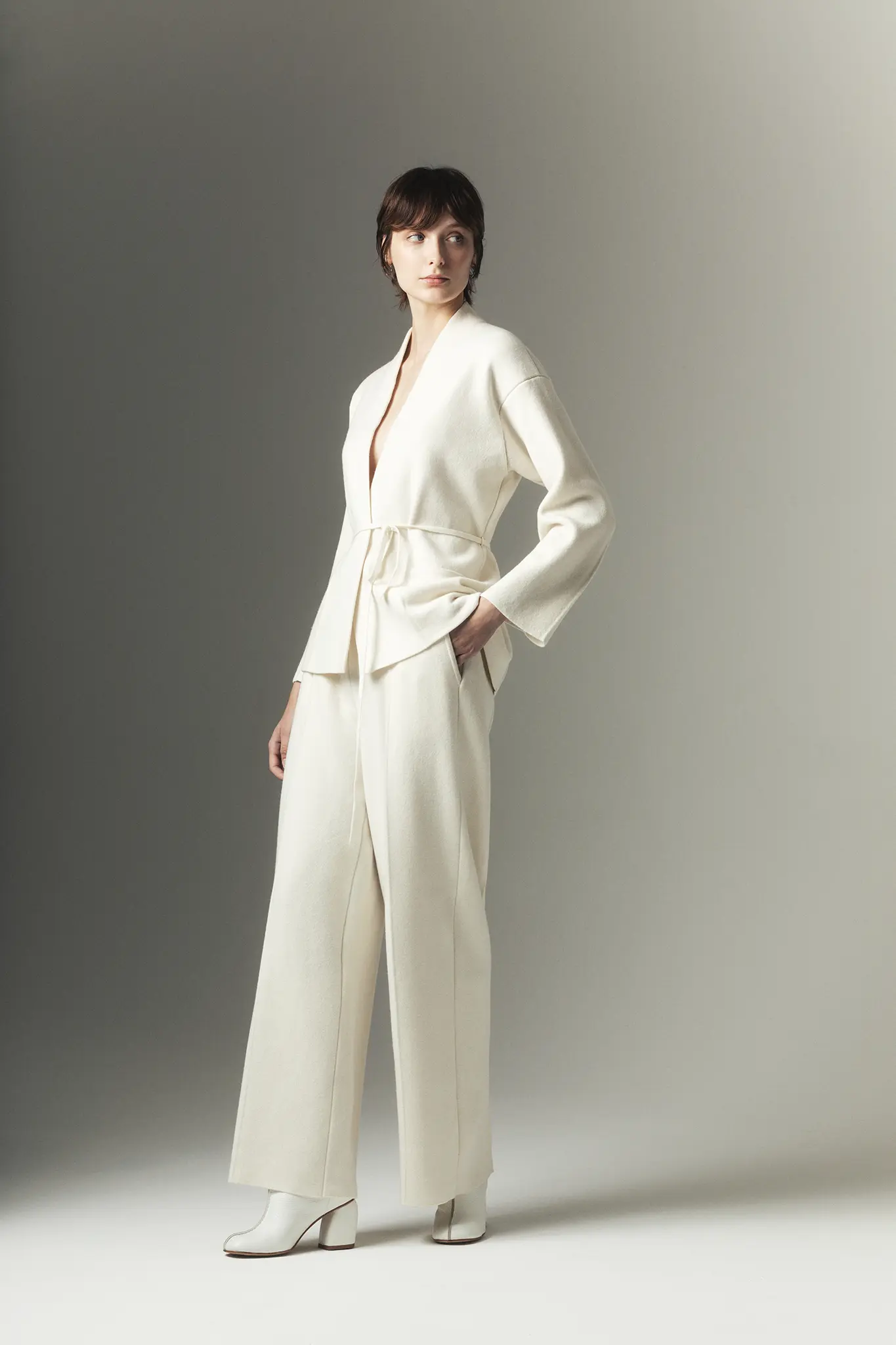 Woman wearing ivory cashmere wrap jacket and wide-leg trousers – Aida Barni Fall Winter 25/26 collection.