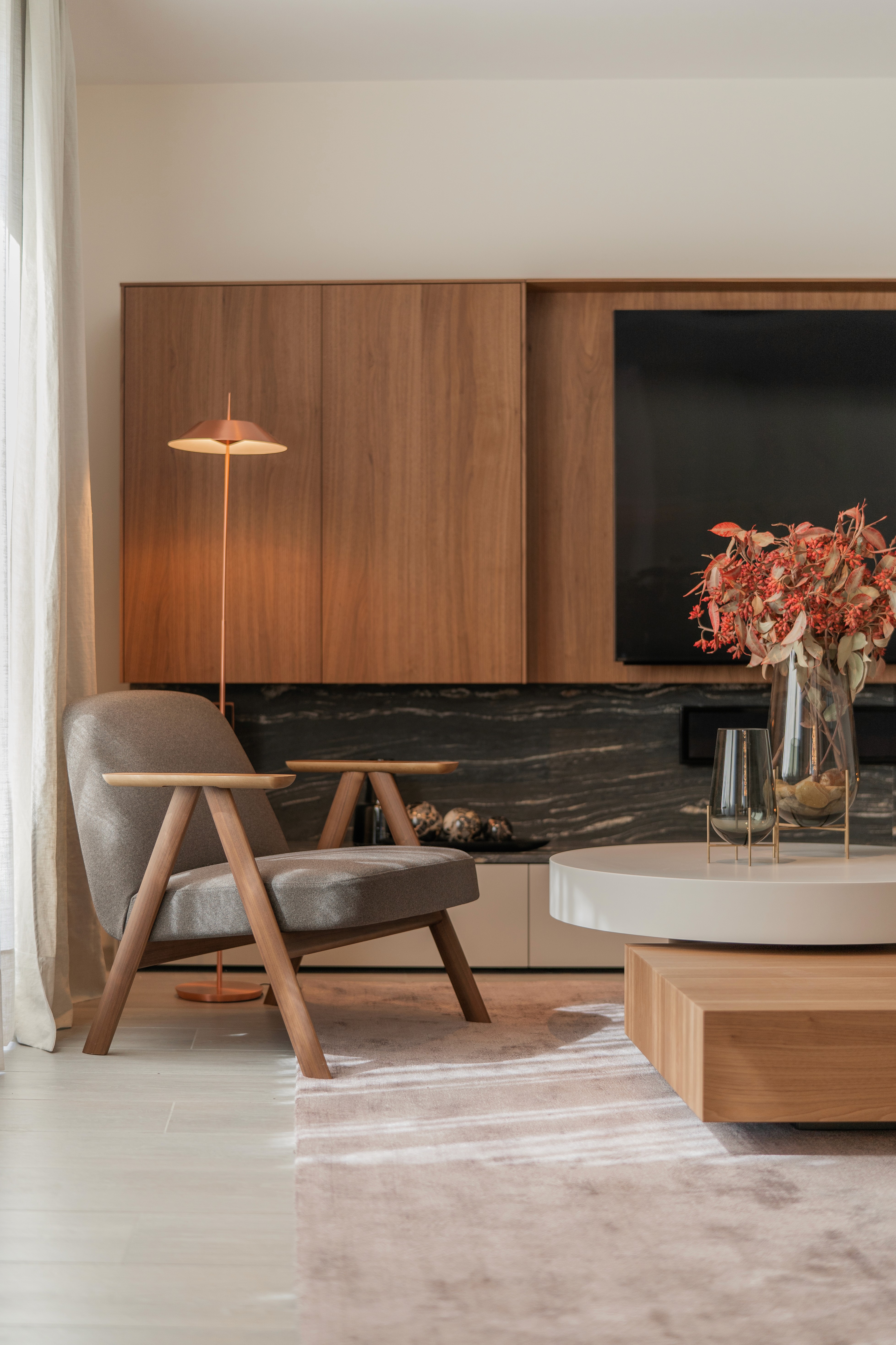 Sillon delante de mueble a medida de madera y mármol oscuro alrededor de la televisión y la chimenea