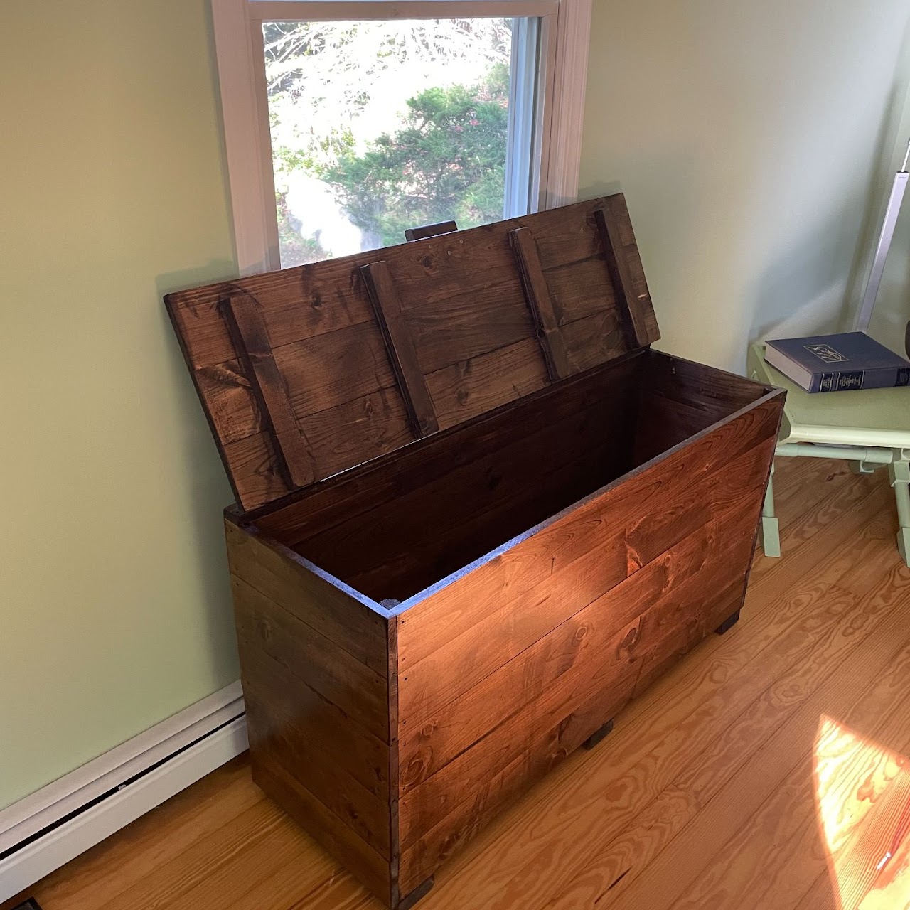 Handcrafted stained wood storage chest with lid open in sunlit room
