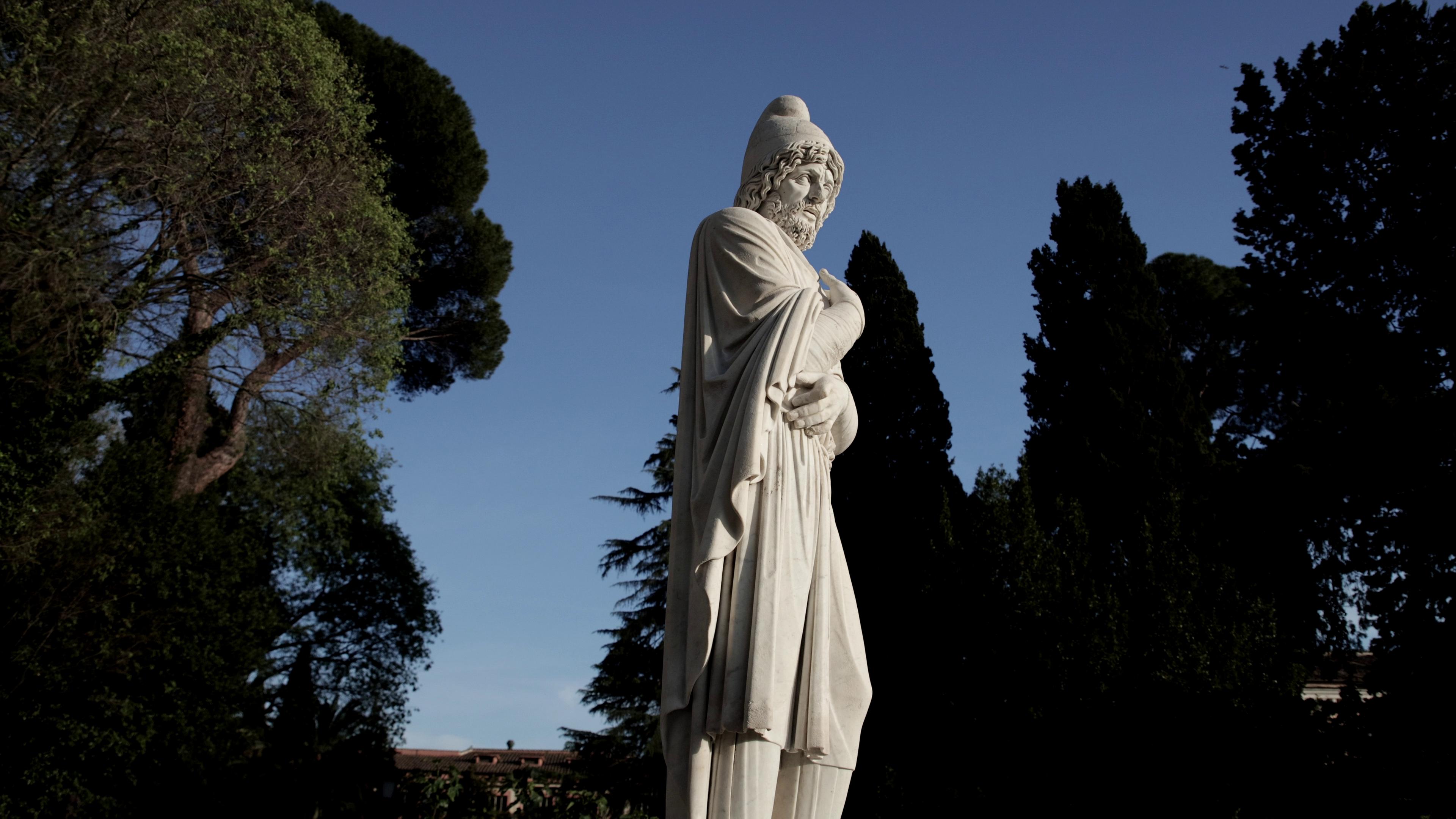 A marble statue in Italy surrounded by trees.