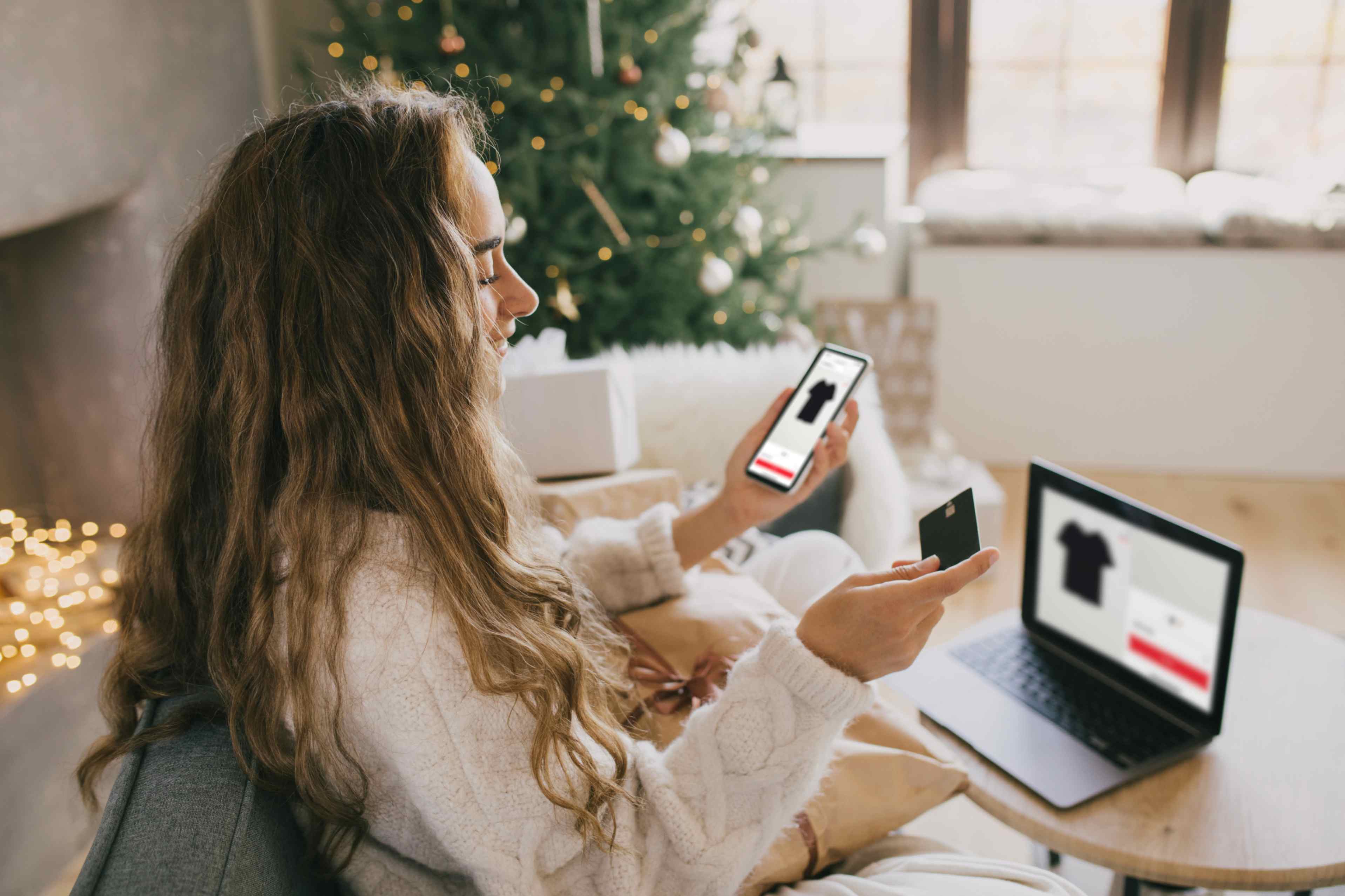 a woman online shopping on their phone with credit card in their other hand