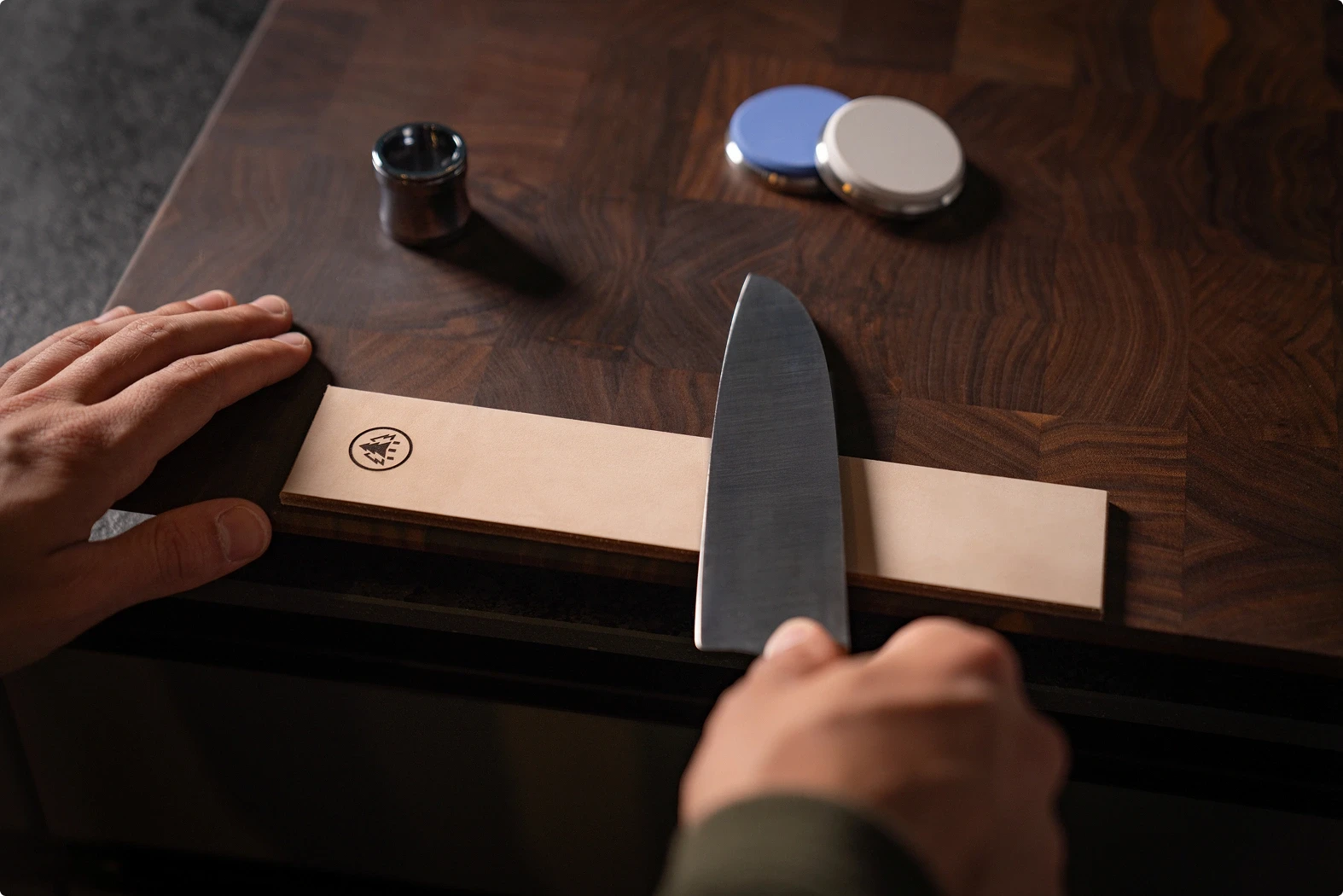 Correct blade positioning on the leather strop, holding the knife at a slight angle with the cutting edge facing left.