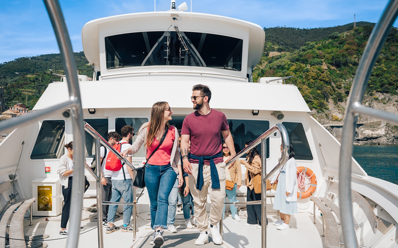 在五漁村的日間旅行中，一對情侶坐在船上，背後是海岸風光。