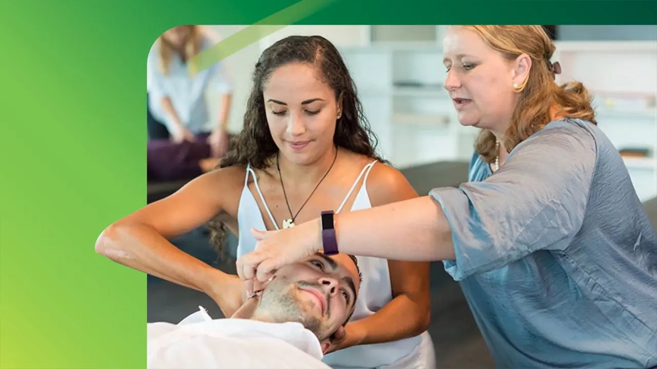 A student adjusts a patient’s neck while a lecturer guides her hands