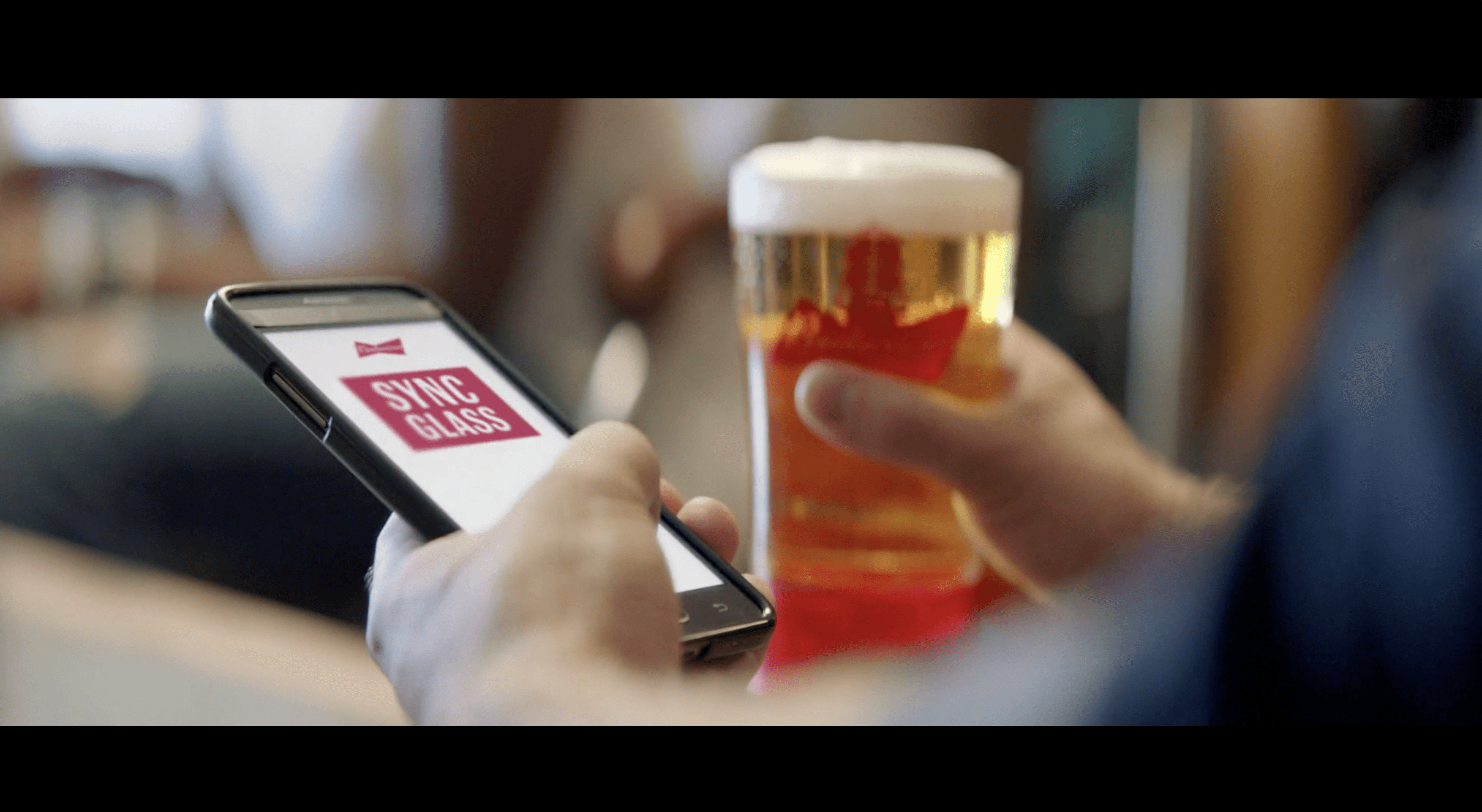 Image of a person holding a beer and using the Budweiser app