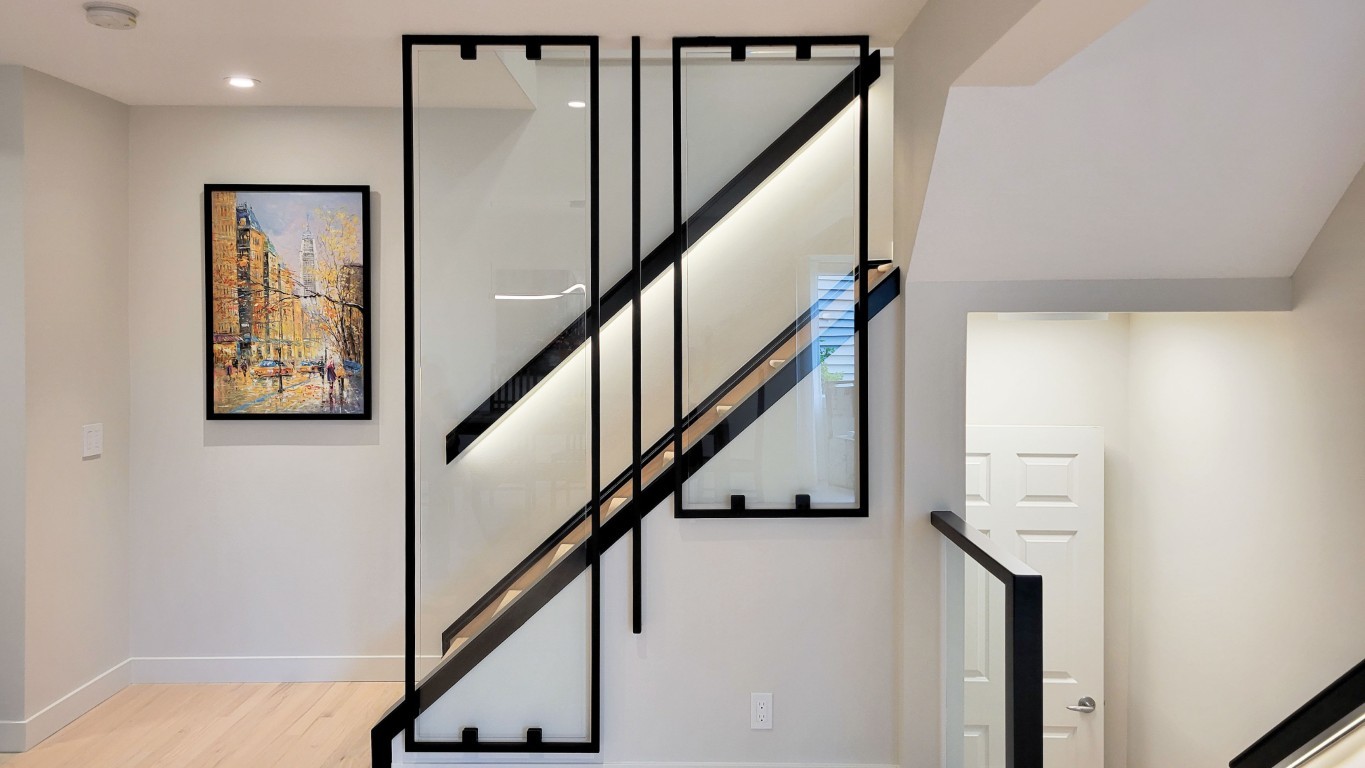 Image of Modern staircase with glass panels and black metal frame in a KHD Homes design-build renovation project.