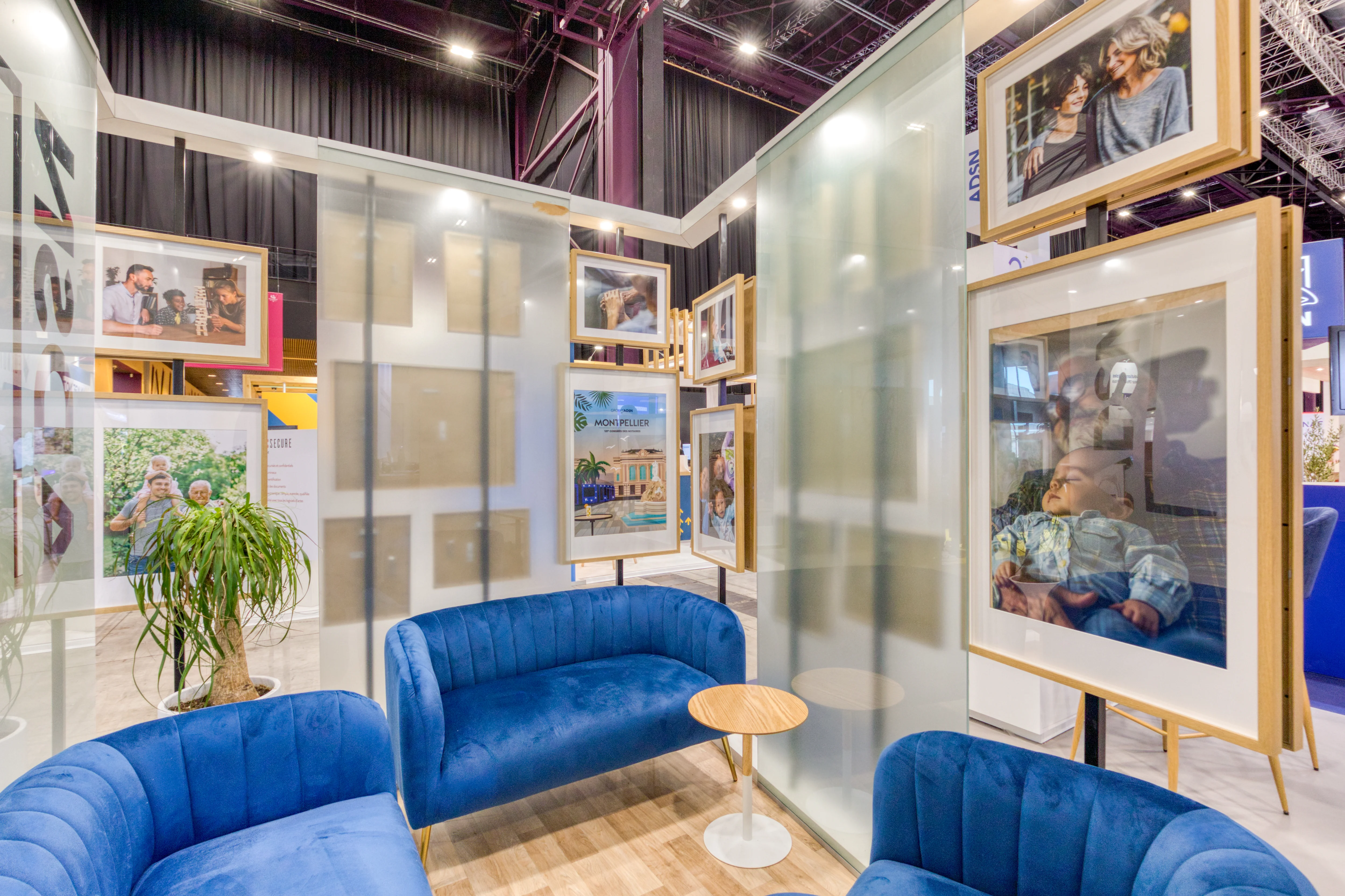 espace lounge du stand ADSN avec fauteuils bleus et cadres suspendus au Congrès des Notaires 2025