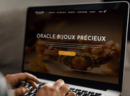 Mockup du site Oracle Bijoux Précieux affiché sur ordinateur portable, montrant la page d’accueil avec un bracelet artisanal en gros plan et bouton Découvrir.