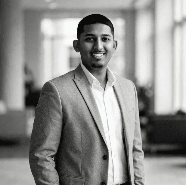 Portrait of a woman with straight long hair, in a dark t-shirt, set against a neutral backdrop.