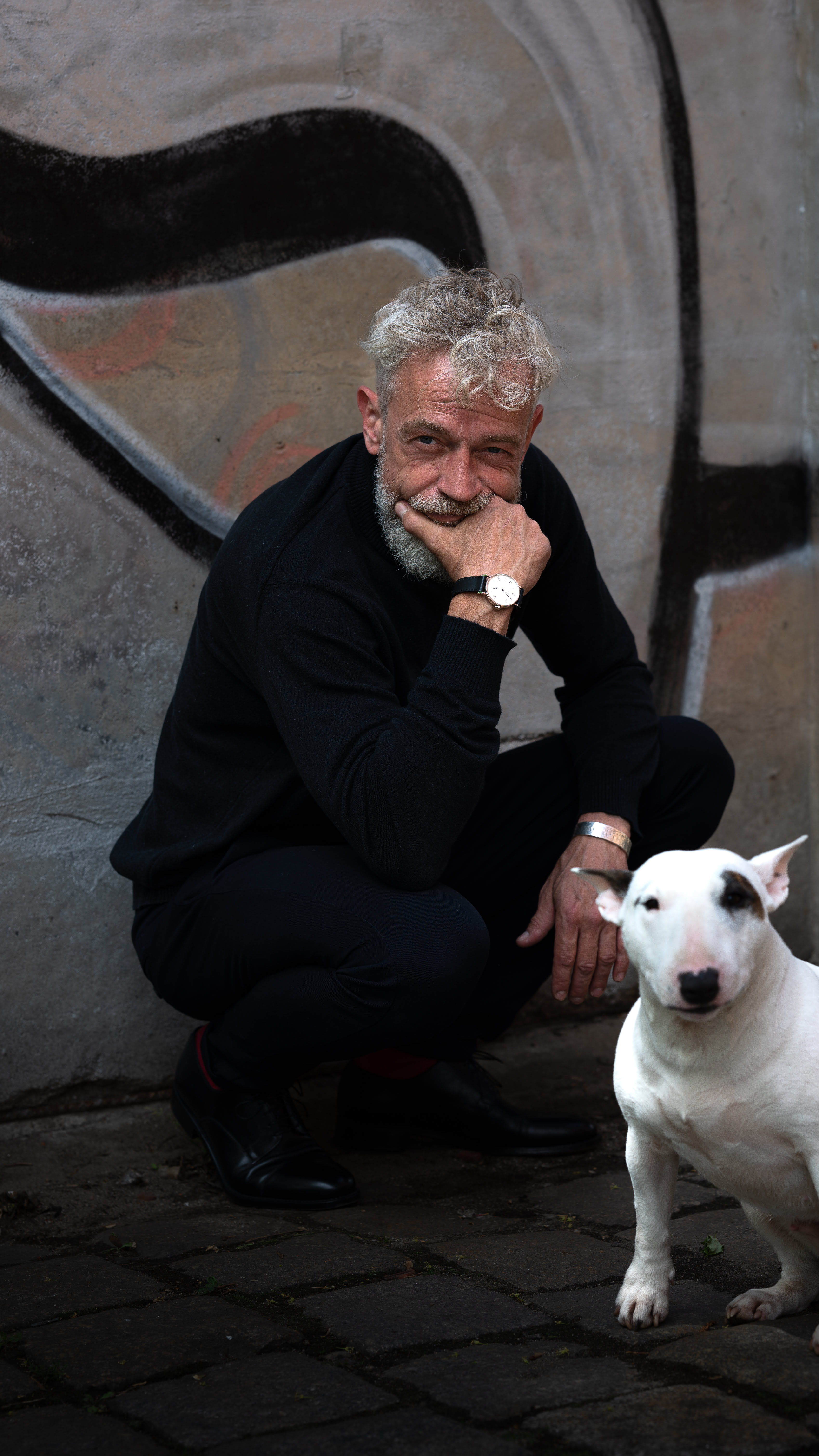 Best Ager hockt mit Hund Hand am  Kinn mit Uhr commercial Szene