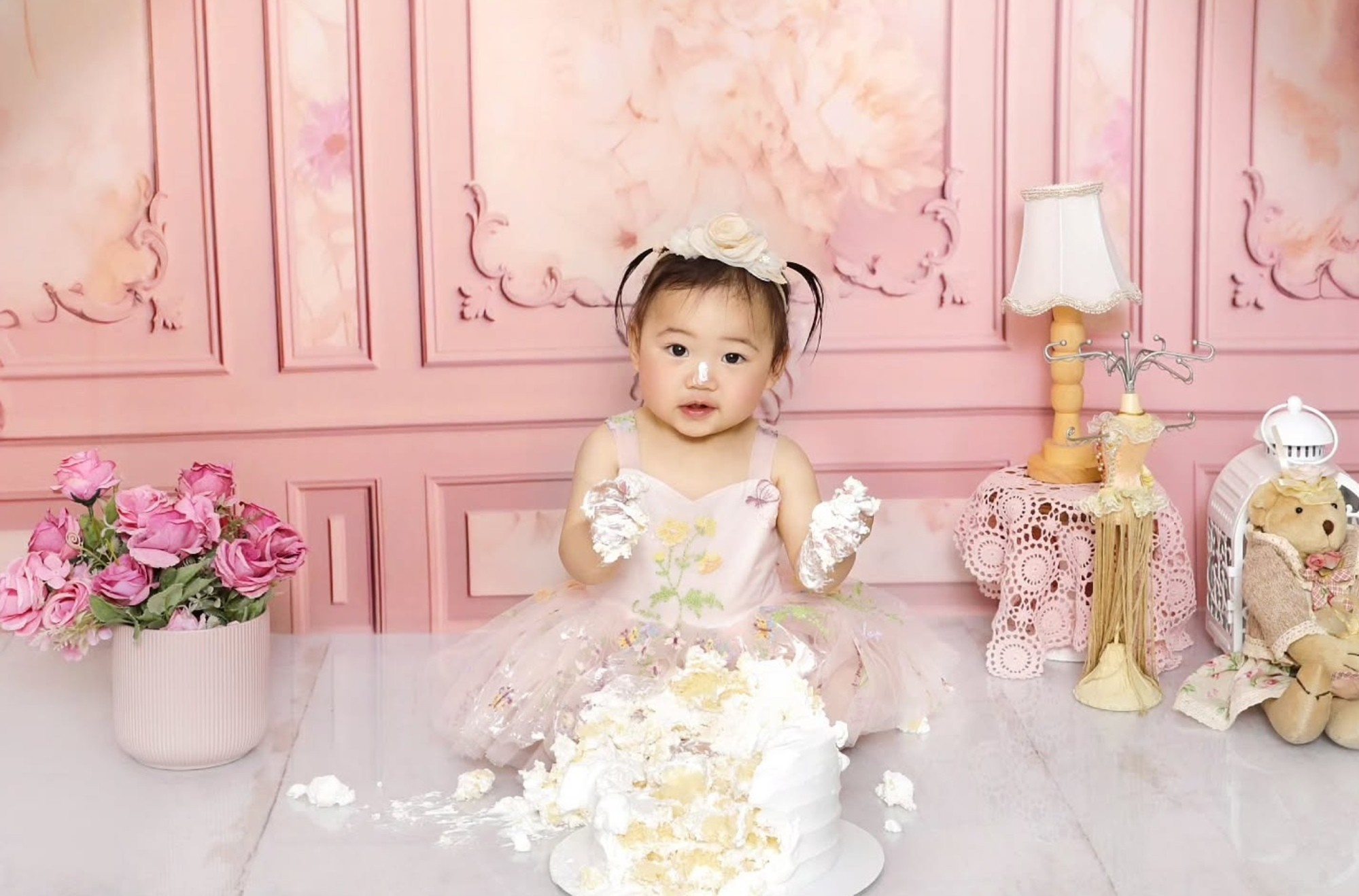 Messy toddler happily doing a smash cake photoshoot during a fun birthday session, captured by Mahvin Photography in Dubai, UAE