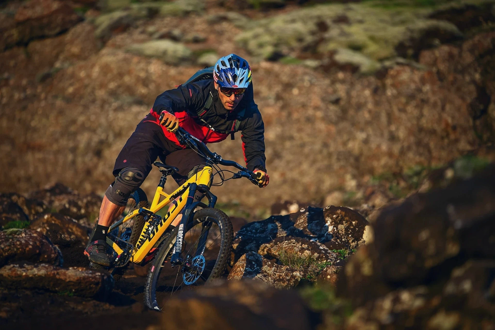 Mountain biker leaning into a turn on a rocky trail in warm light.