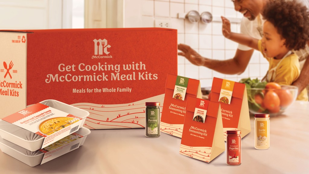 McCormick delivery packaging with spice kits, spices, and prep meals, with a father and son in the background.