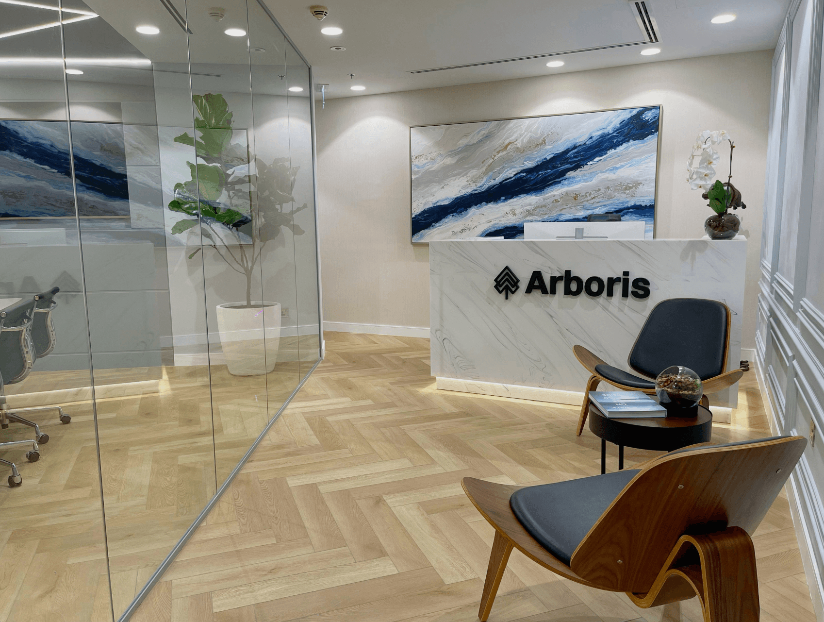 Modern interior space with a blue circular coffee table, flowers in a vase, and books neatly arranged.