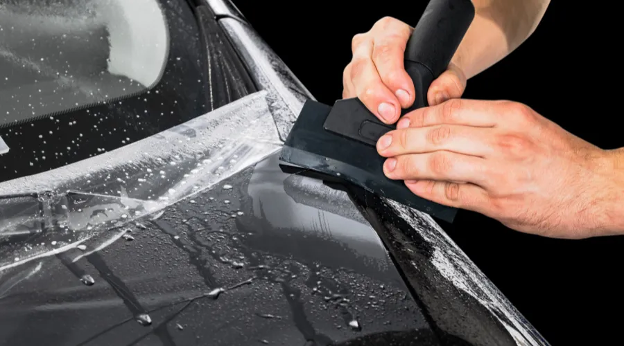 Applying protective film to car hood with squeegee