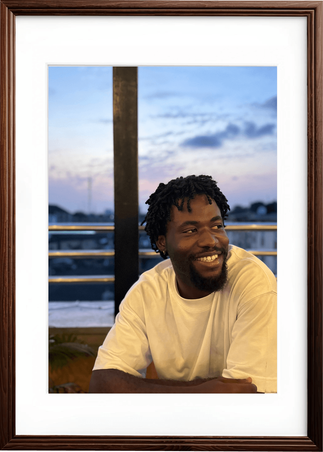 a picture of michael adekolu in a white shirt, smiling and looking sideways