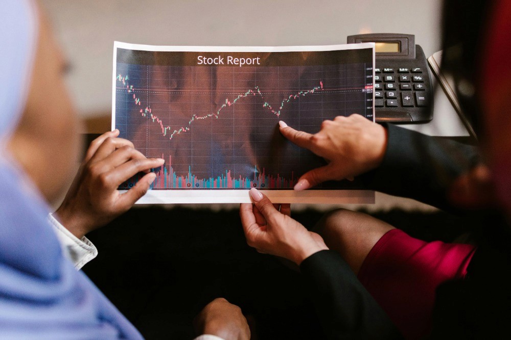 Personas revisando un gráfico financiero impreso para analizar distintos instrumentos de inversión