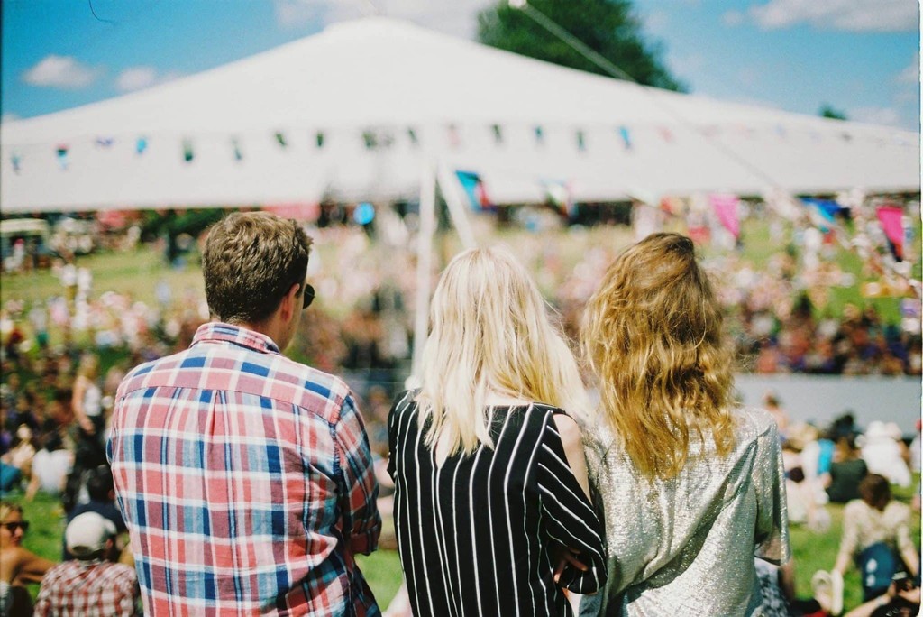Festival crowd with three people enjoying a sunny outdoor event.