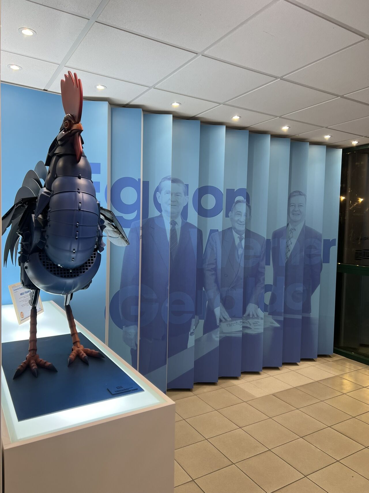 Showroom WEG – Espace d'accueil sur-mesure bleu avec logo mural rétroéclairé, mobilier lounge et écran digital intégré, conçu et réalisé par Expace