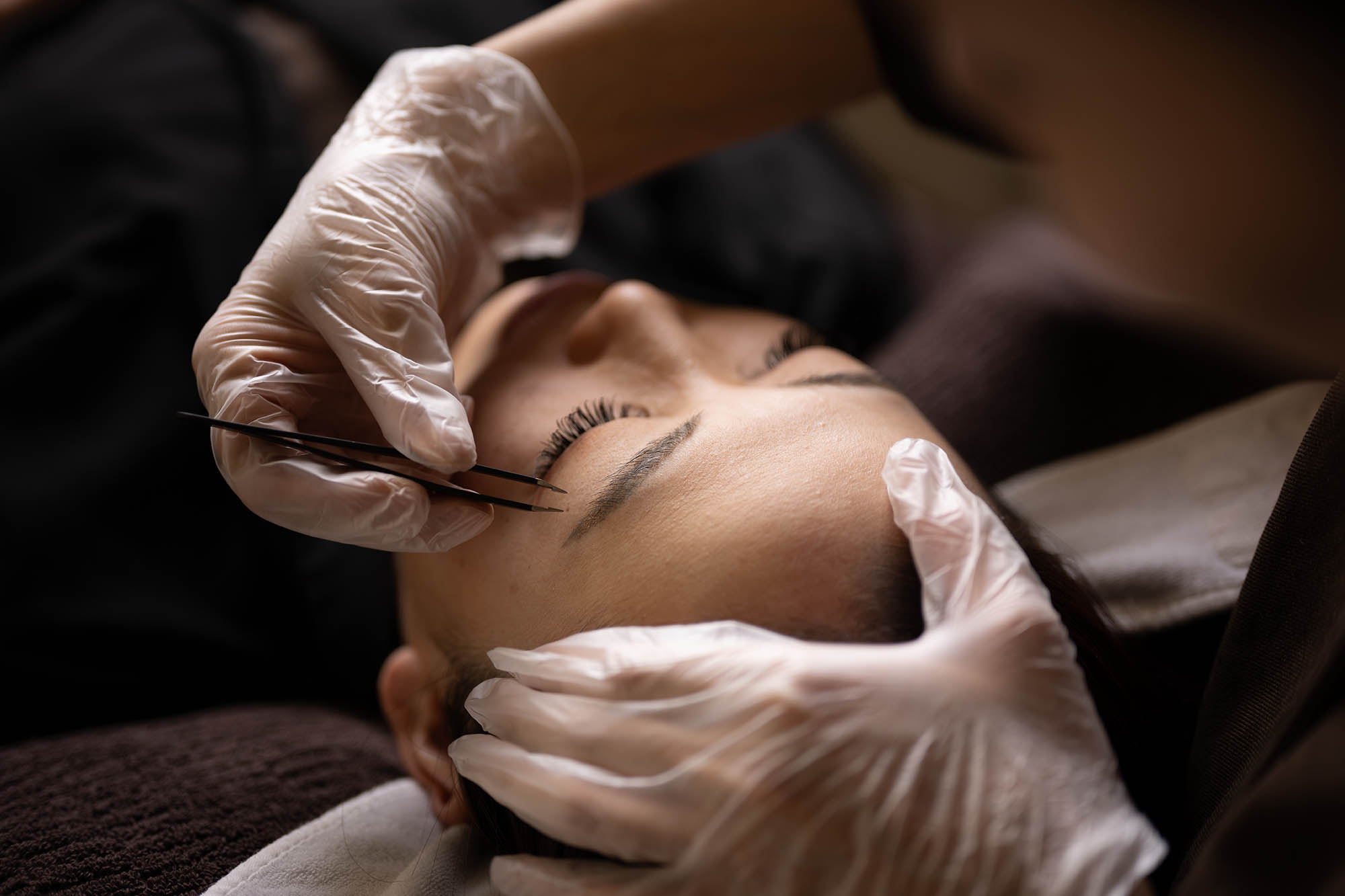 Close-up portrait of a person wearing a gray insulated hooded jacket with the hood up, showing their face framed by the hood against a light background.