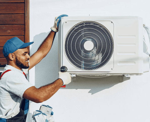 HVAC technician installing a heat pump system on an exterior wall
