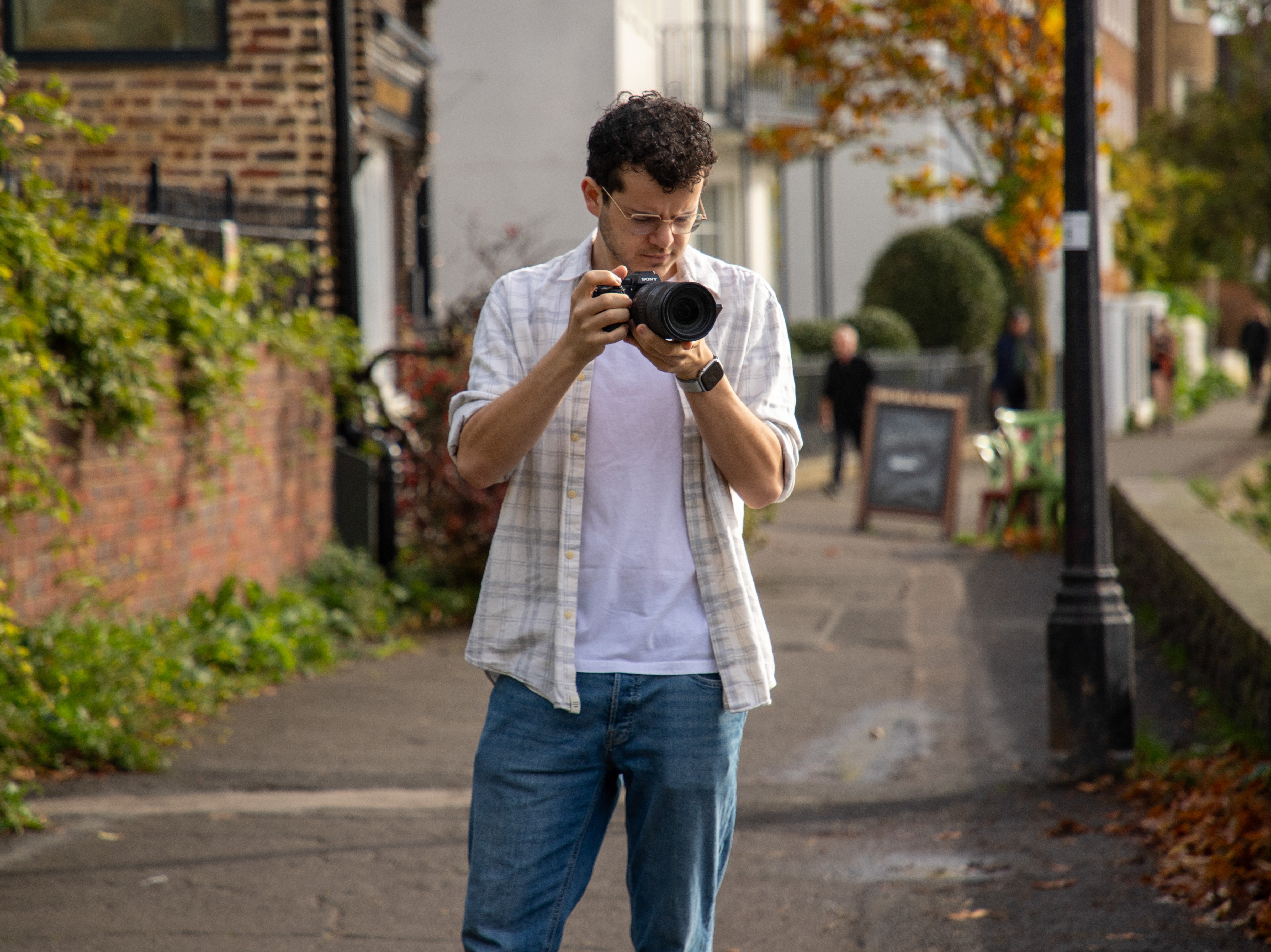 Chris Tailor holding up a Sony A7Siii camera on the Thames Road in Chiswick