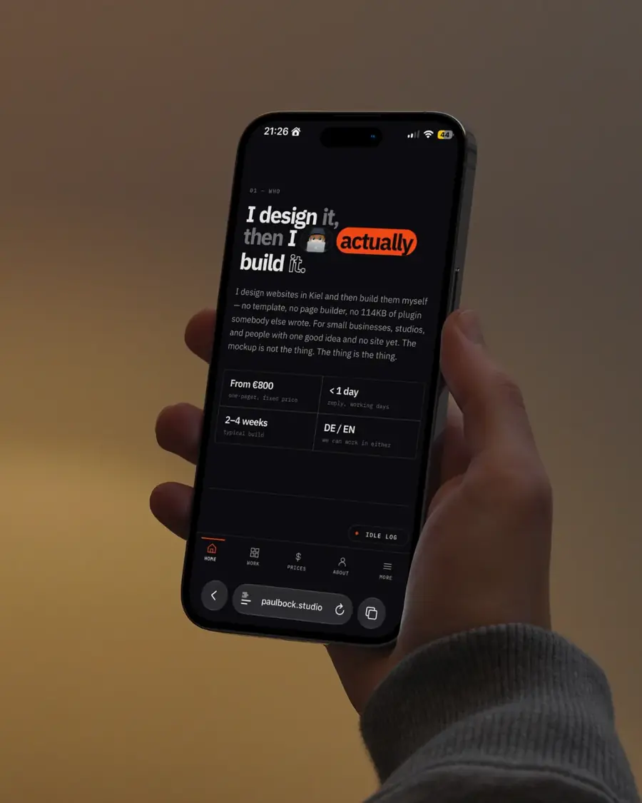 The portfolio site, the finished site on a phone, held in one hand.