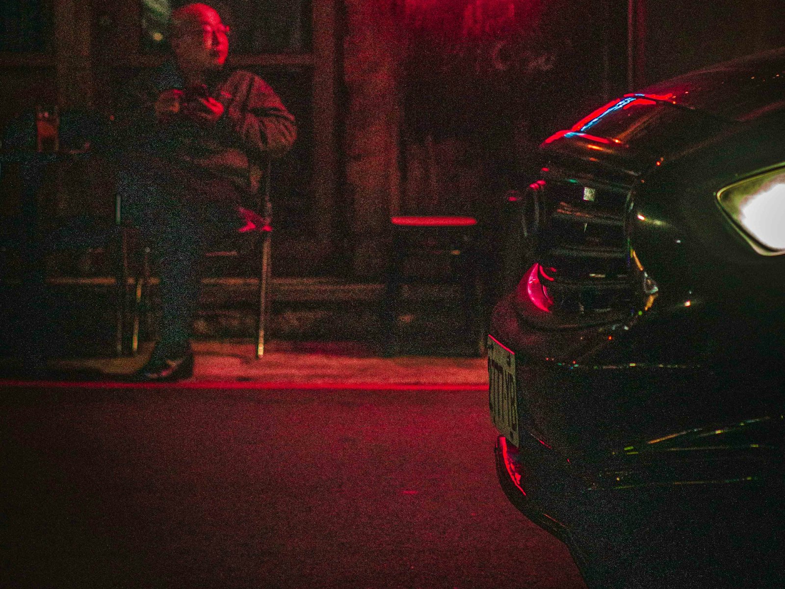 Customer sitting outside a neon-lit cafe at night after paying by card