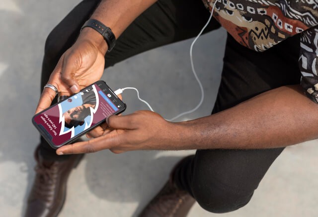 A person holding a smartphone with earphones plugged in.