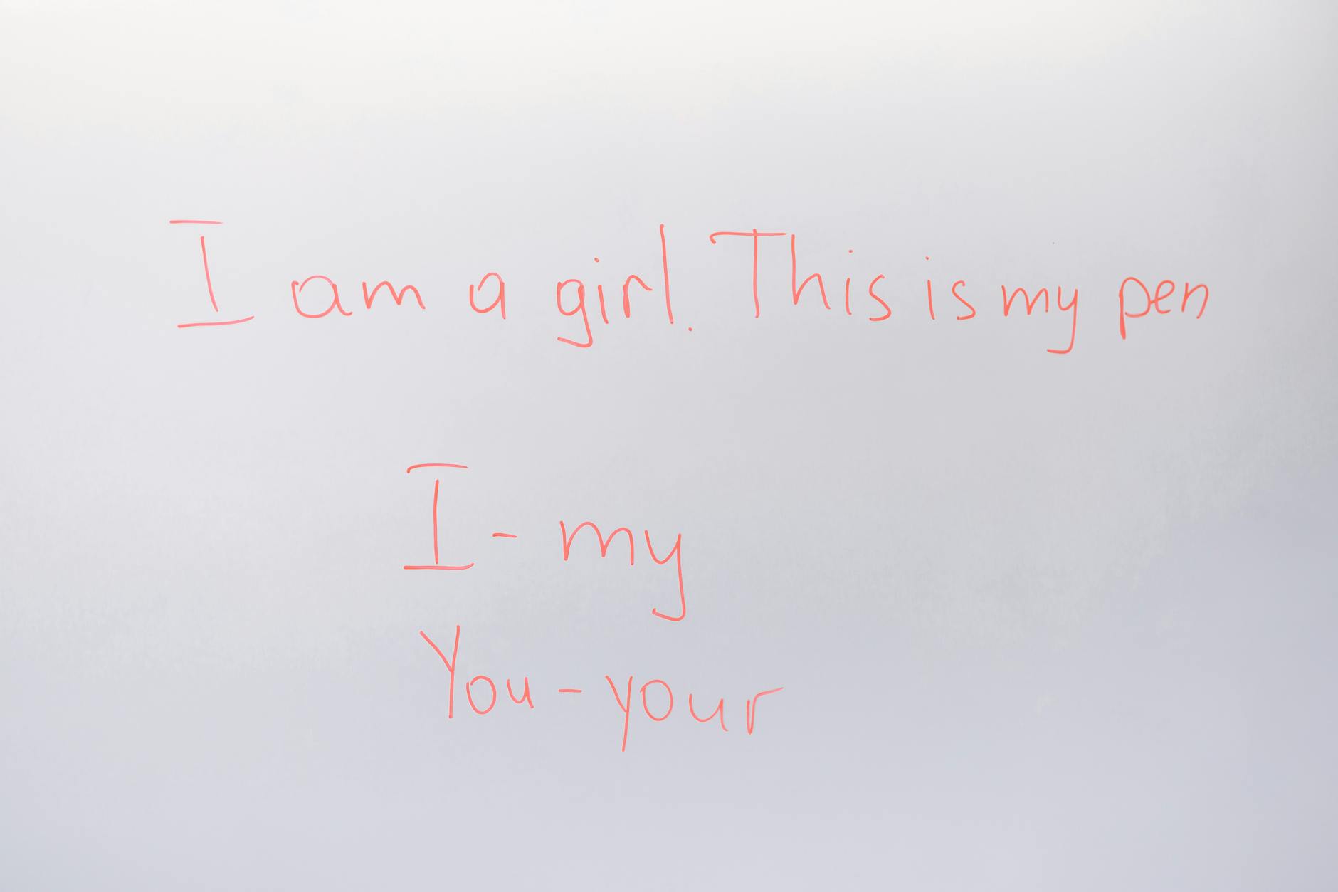 An elementary teacher pointing to a grammar diagram on a large whiteboard while smiling at her students.